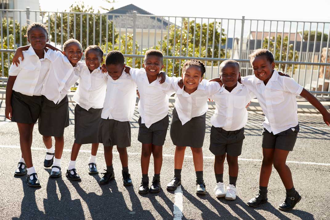A group of happy school learners in uniform, arms around each other